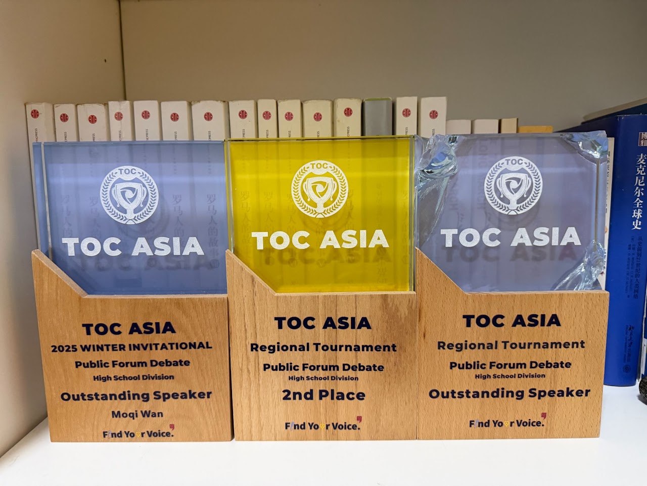Three TOC ASIA debate trophies: 2025 Winter Invitational Outstanding Speaker, plus Regional Tournament 2nd Place and Outstanding Speaker