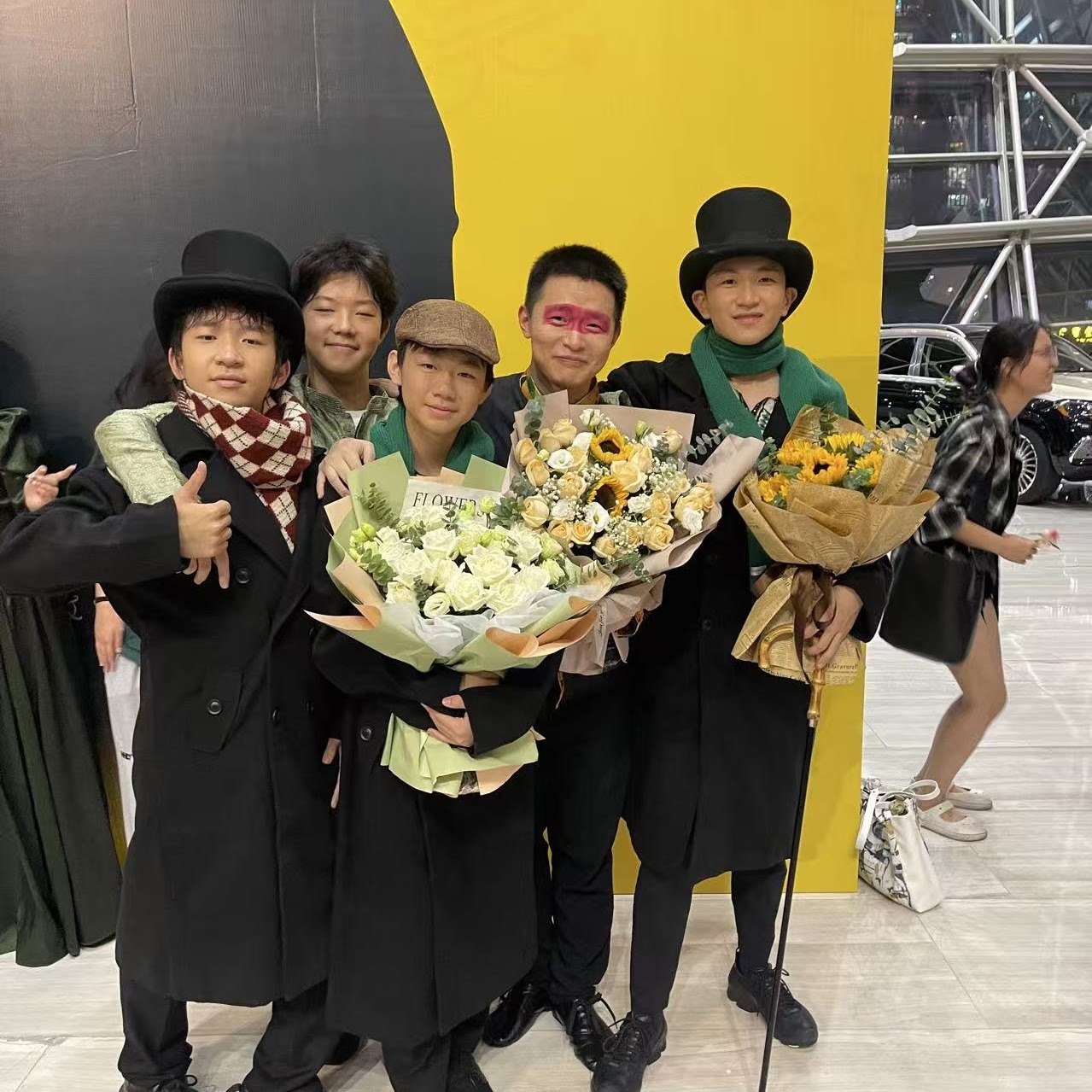 Cast of a school musical posing together with bouquets after the show